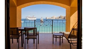 Un balcon avec vue sur la mer, offrant un panorama sur un navire de croisière et une côte rocheuse.