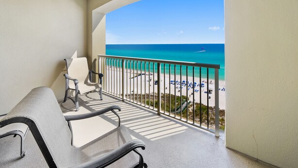 A balcony with two chairs and a view of the beach. - Grand Panama 904 Gulf Front & Pet Friendly, Sleeps 9 (Panama City Beach)