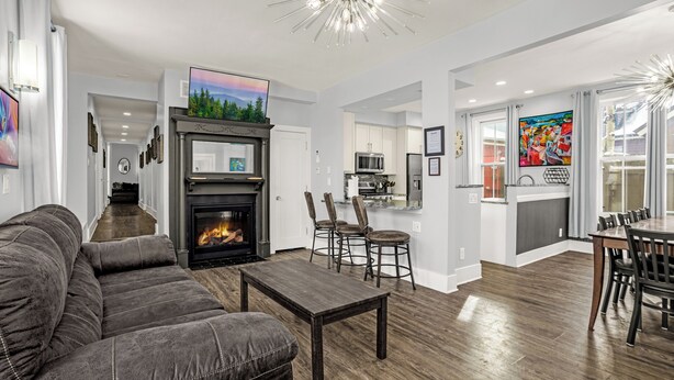 A modern living room with a fireplace, a dining area, and a kitchen. - Downtown Breck~7BR&7BA~Walk to Gondola~Hot Tub~AC~3 Parking Spots (Breckenridge)