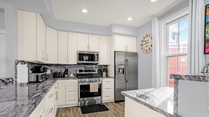 A modern kitchen with white cabinets, stainless steel appliances, and a large window. - Downtown Breck~7BR&7BA~Walk to Gondola~Hot Tub~AC~3 Parking Spots (Breckenridge)