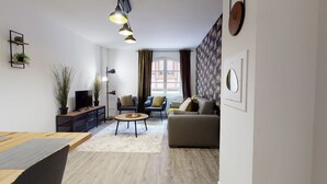Uma sala de estar moderna com televisão, sofá, poltronas e mesa de centro.