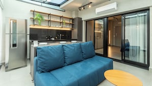 A modern kitchen with a blue sofa, a wooden table, and a skylight. - Charlie Oscar Freire (São Paulo)