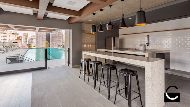 A modern kitchen with a bar area, large windows, and a view of the cityscape. - Charlie Oscar Freire (São Paulo)