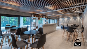 A modern interior with a wooden ceiling, black chairs, and tables arranged around a central counter. - Charlie Oscar Freire (São Paulo)