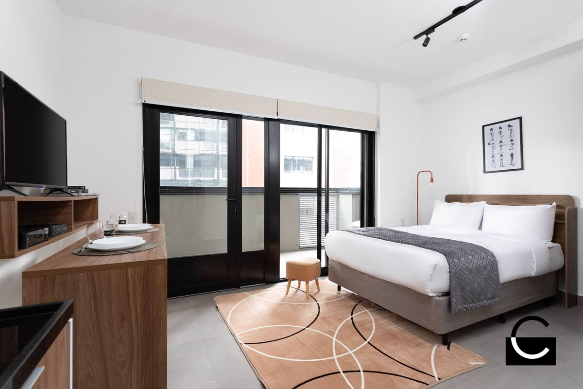 Ein modernes Hotelzimmer mit Bett, Schreibtisch, Fernseher und einem großen Fenster.