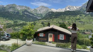 Blick vom Balkon auf eine gebirgige Landschaft mit einer Holzhütte.
