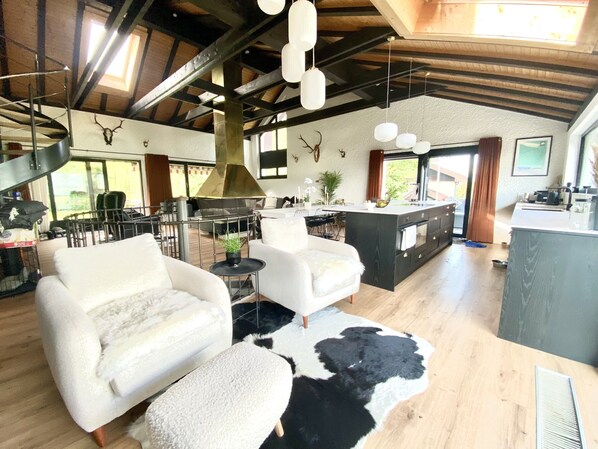 Un amplio salón con techo alto, una isla central con estufa y un comedor con sillas y mesa.