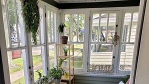 A sunroom with a wooden bench, potted plants, and a cushioned seating area. - IN TOWN, ONLY 3 BLOCKS FROM LAKE MICHIGAN’S “STEARNS BEACH”! (Ludington)
