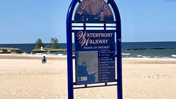 A signboard titled "Ludington Waterfront Walkway" listing points of interest like Stearns Park, Beach & Lighthouse, and City Hall. - IN TOWN, ONLY 3 BLOCKS FROM LAKE MICHIGAN’S “STEARNS BEACH”! (Ludington)