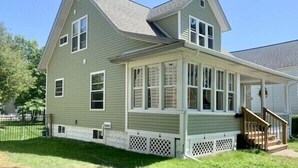 A two-story house with a covered porch and a front staircase. - IN TOWN, ONLY 3 BLOCKS FROM LAKE MICHIGAN’S “STEARNS BEACH”! (Ludington)