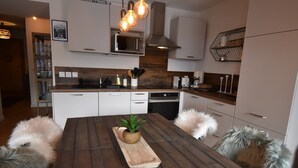 Una cocina moderna con armarios blancos, una mesa de comedor de madera y una isla central con una planta.