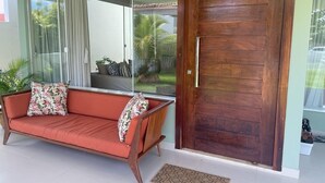 Ein modernes Wohnzimmer mit einer Couch, einer Holztür und einer Glastür, die auf einen Balkon führt.