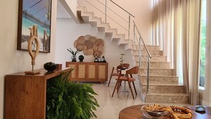 Ein modernes Wohnzimmer mit Treppe, Holzmöbeln und einer großen Pflanze.