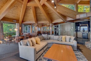 A spacious living area with a large sectional sofa, a wooden coffee table, and a dining area with chairs and a table.
