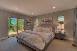 Ein Schlafzimmer mit einem großen Bett, einem Nachttisch, einem Gemälde und einer Glastür zu einem Balkon.