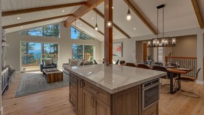 A spacious kitchen with a large island, wooden beams, and pendant lighting.