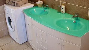 Een badkamer met een wasmachine, twee wastafels en een spiegel.