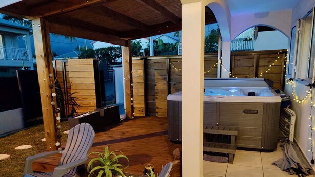 Een terras buiten met een jacuzzi, een houten terras en zitplaatsen.