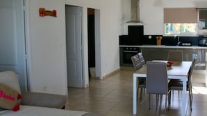 Een moderne keuken met een fornuis, magnetron en een eethoek met stoelen en een tafel.