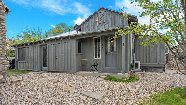 Un chalet rustique avec une allée en gravier et une terrasse en bois.