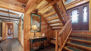 A wooden interior with a staircase, a mirror, and a table with a lamp.