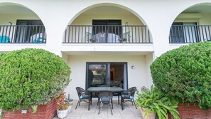 Ein zweigeschossiges Gebäude mit Balkon, Glastür und Außenbereich mit Stühlen und Tisch.