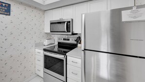 A modern kitchen with stainless steel appliances, including a microwave, oven, and refrigerator. There is a toaster and a coffee maker on the countertop.