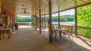 A covered outdoor deck with a table and chairs, a grill, and a view of a lake. - Ducktail Pointe - private launch ramp and dock! (Houston)