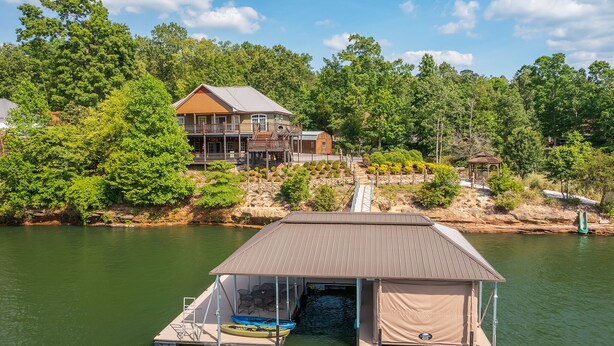 A lakeside property with a dock, a covered boat storage area, and a house with a deck. - Ducktail Pointe - private launch ramp and dock! (Houston)