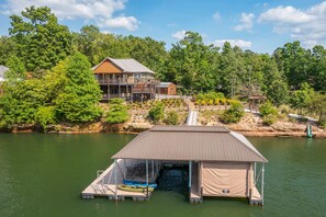 A lakeside property with a dock, a covered boat storage area, and a house with a deck. - Ducktail Pointe - private launch ramp and dock! (Houston)