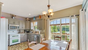 A kitchen with a dining area, featuring a large window, wooden table, and cabinets. - Ducktail Pointe - private launch ramp and dock! (Houston)