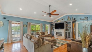 A spacious living room with a large sofa set, a fireplace, and a ceiling fan. - Ducktail Pointe - private launch ramp and dock! (Houston)