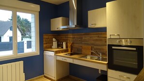 A modern kitchen with a dishwasher, oven, and wooden backsplash. - Ravissant ! Le Panorama - Vue Mer (Criel-sur-Mer)