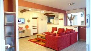 A modern living room with a red sofa, wooden flooring, and a TV on a stand. - Ravissant ! Le Panorama - Vue Mer (Criel-sur-Mer)
