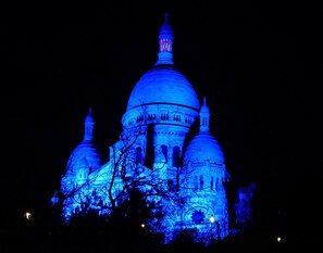 A large domed building with multiple smaller domes and towers, illuminated in blue.