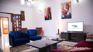 Een moderne woonkamer met een bank, fauteuils, een salontafel en een televisie.