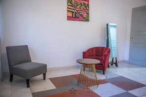 A room with a grey armchair, a red armchair, and a small round table with a gold base. - Premier Residence at the heart of Dakar (Dakar)