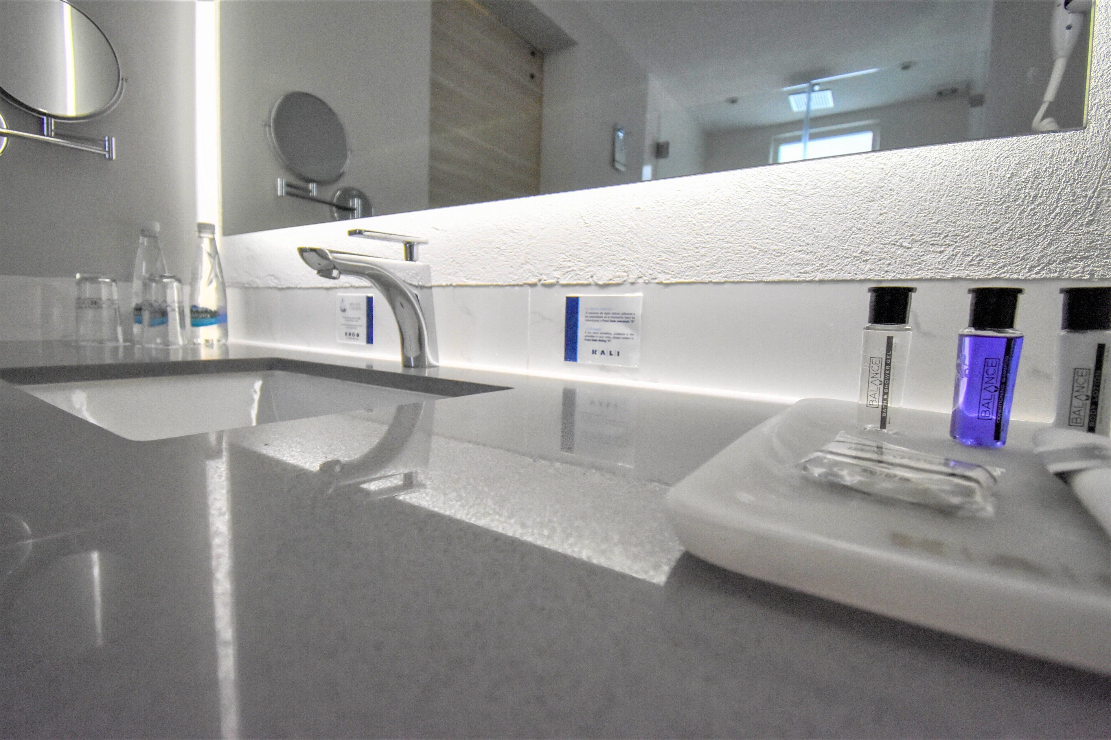 A modern bathroom with a large mirror, a sink, and a vanity area.