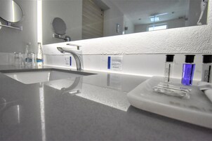 Une salle de bain moderne avec un grand miroir, un lavabo et un espace coiffeuse.
