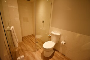 Un bagno con doccia vetrata, un water e un porta asciugamani.