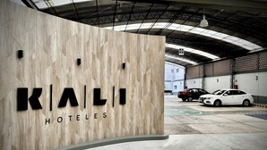 Ein Hotel Eingang mit einer Holzfassade und der Schriftzug "KALI HOTELS" gut sichtbar.