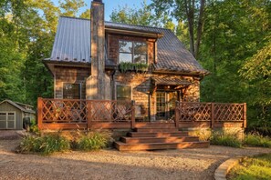 A two-story wooden cabin with a metal roof, a front porch with steps, and a fenced yard. - (2027 OPEN!) Lake View Home with Private Pool and Hot Tub! (Harbert)