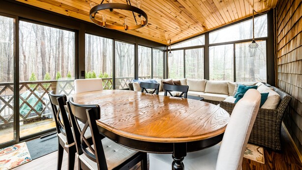 Une terrasse en bois avec une table ronde et des chaises, un canapé et un luminaire suspendu.