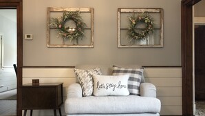 Una sala de estar con un sofá gris, dos espejos decorativos en la pared y una pequeña mesa auxiliar de madera.