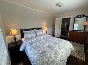A bedroom with a bed, two bedside lamps, a dresser, and a mirror.