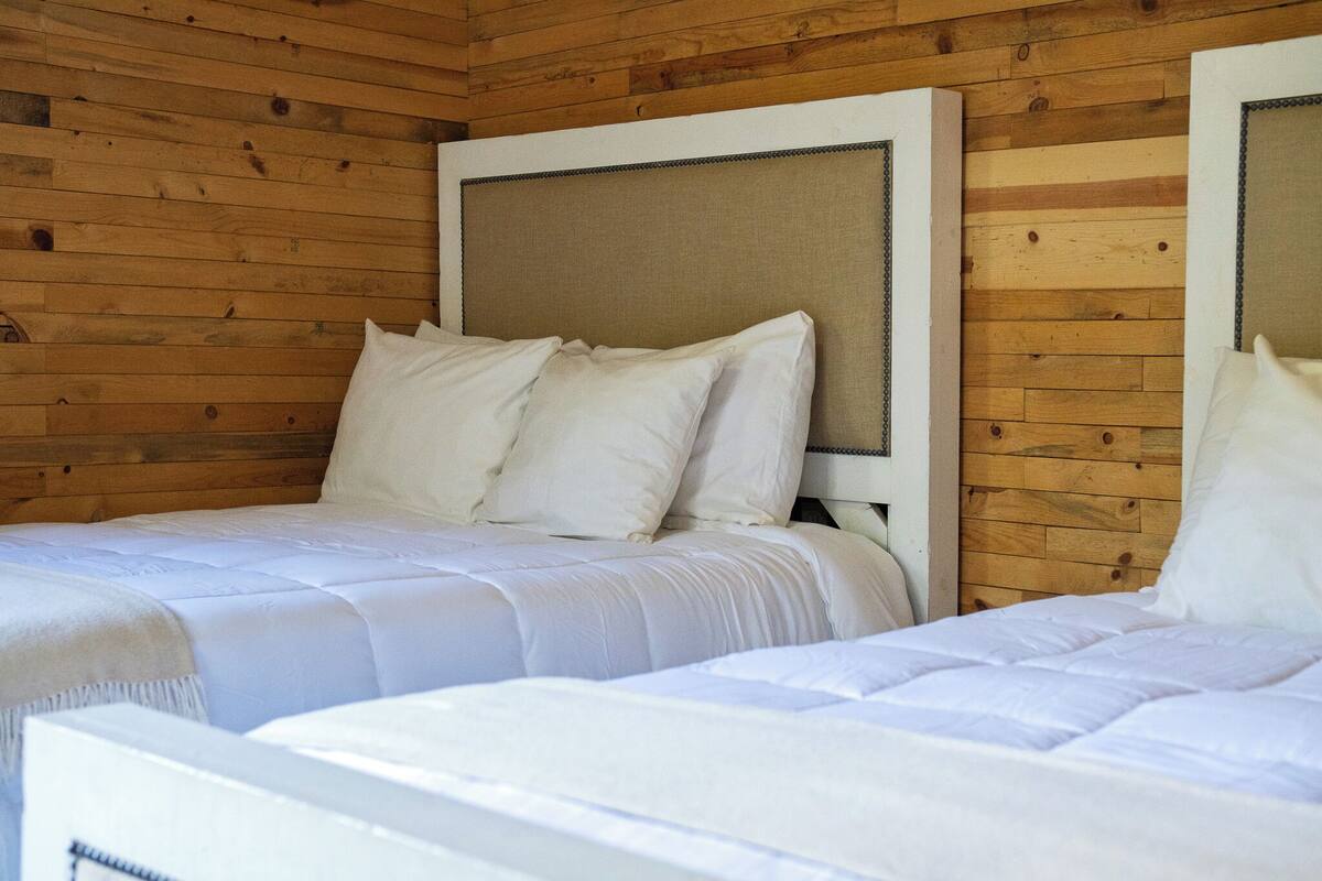 Ein Schlafzimmer einer Holzhütte mit zwei Betten, jeweils mit weißer Bettwäsche und Kopfteilen.
