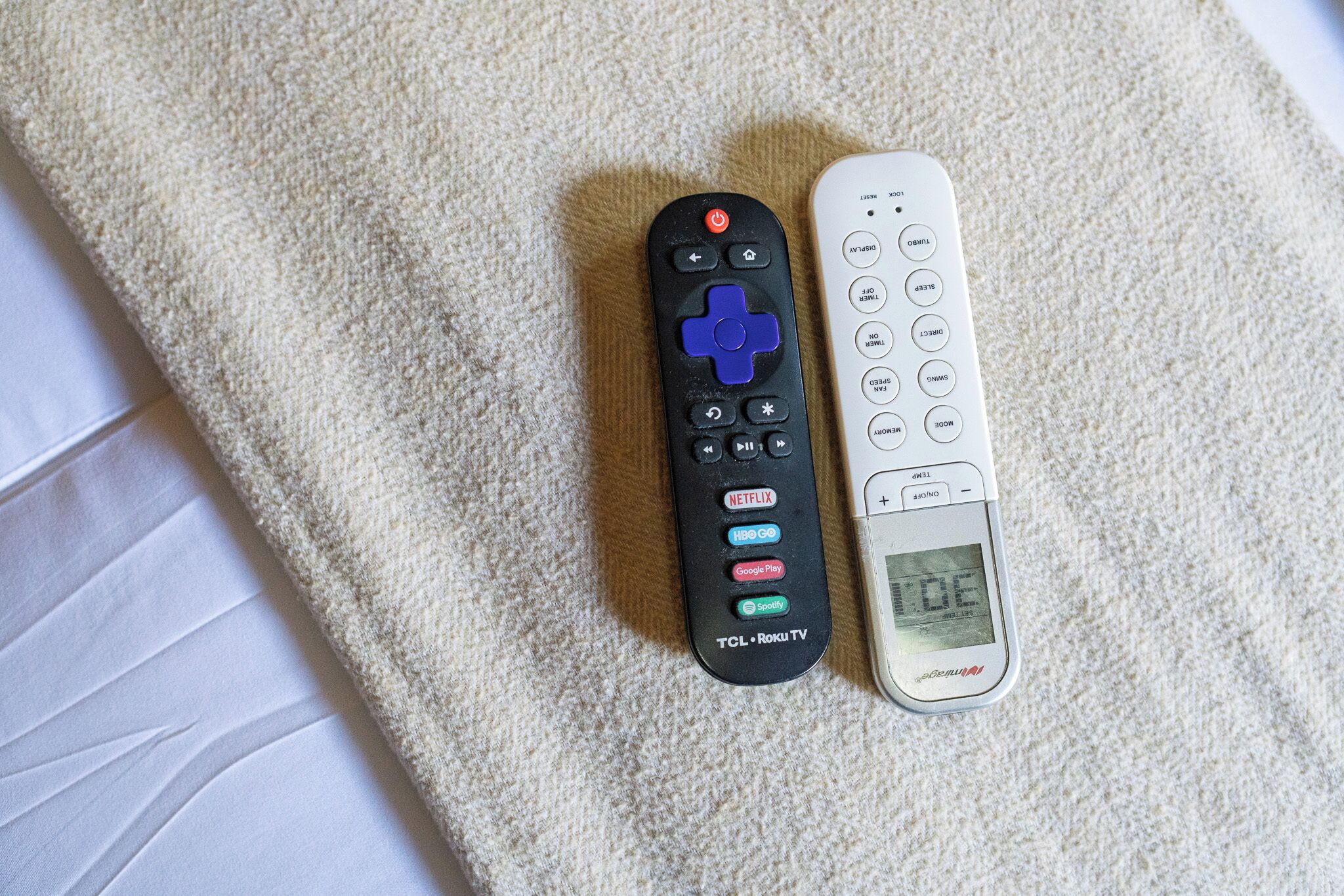 Two remote controls on a textured surface.