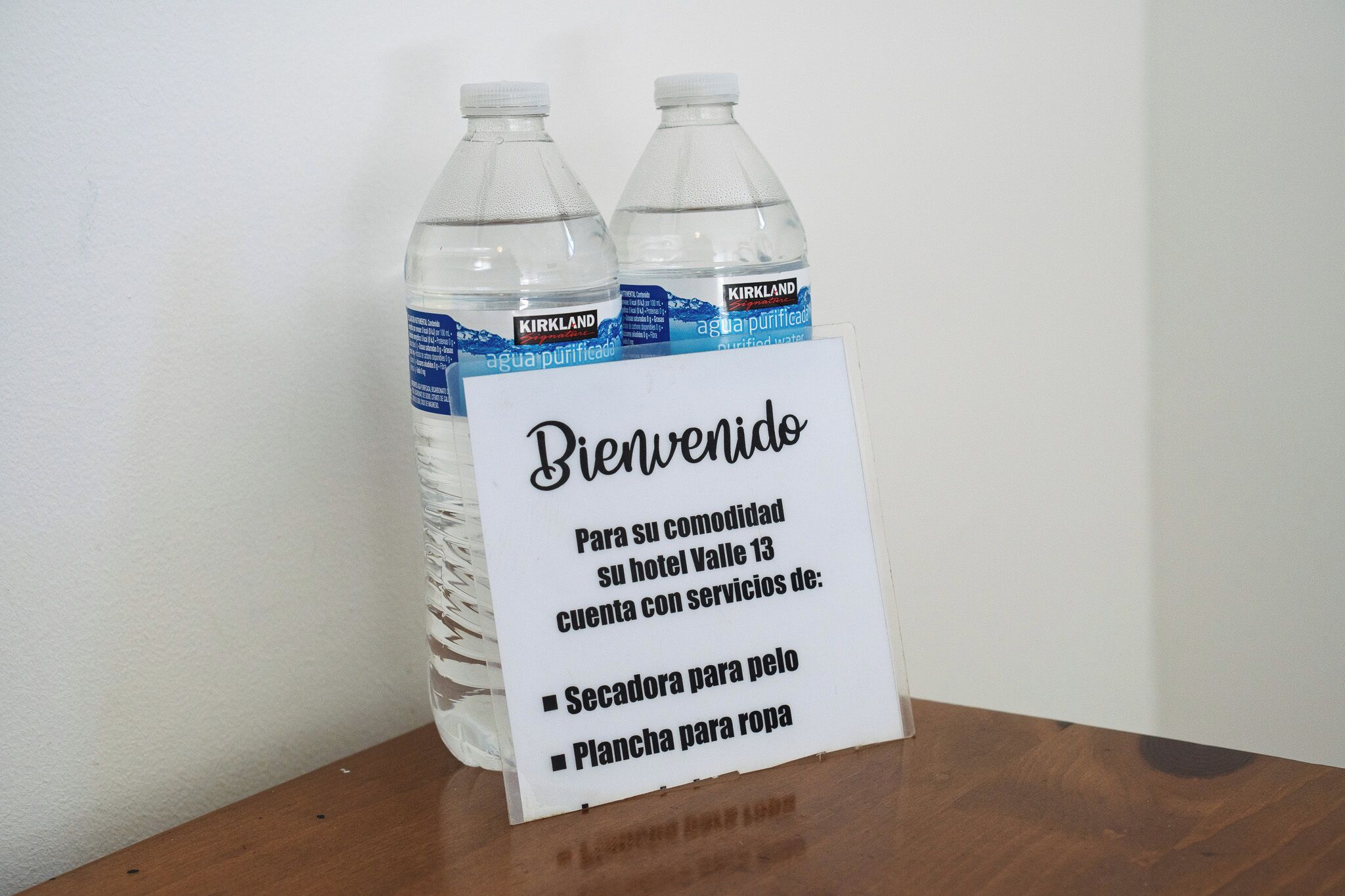 A welcome sign with two Kirkland water bottles and a list of services at Valle 13 hotel.