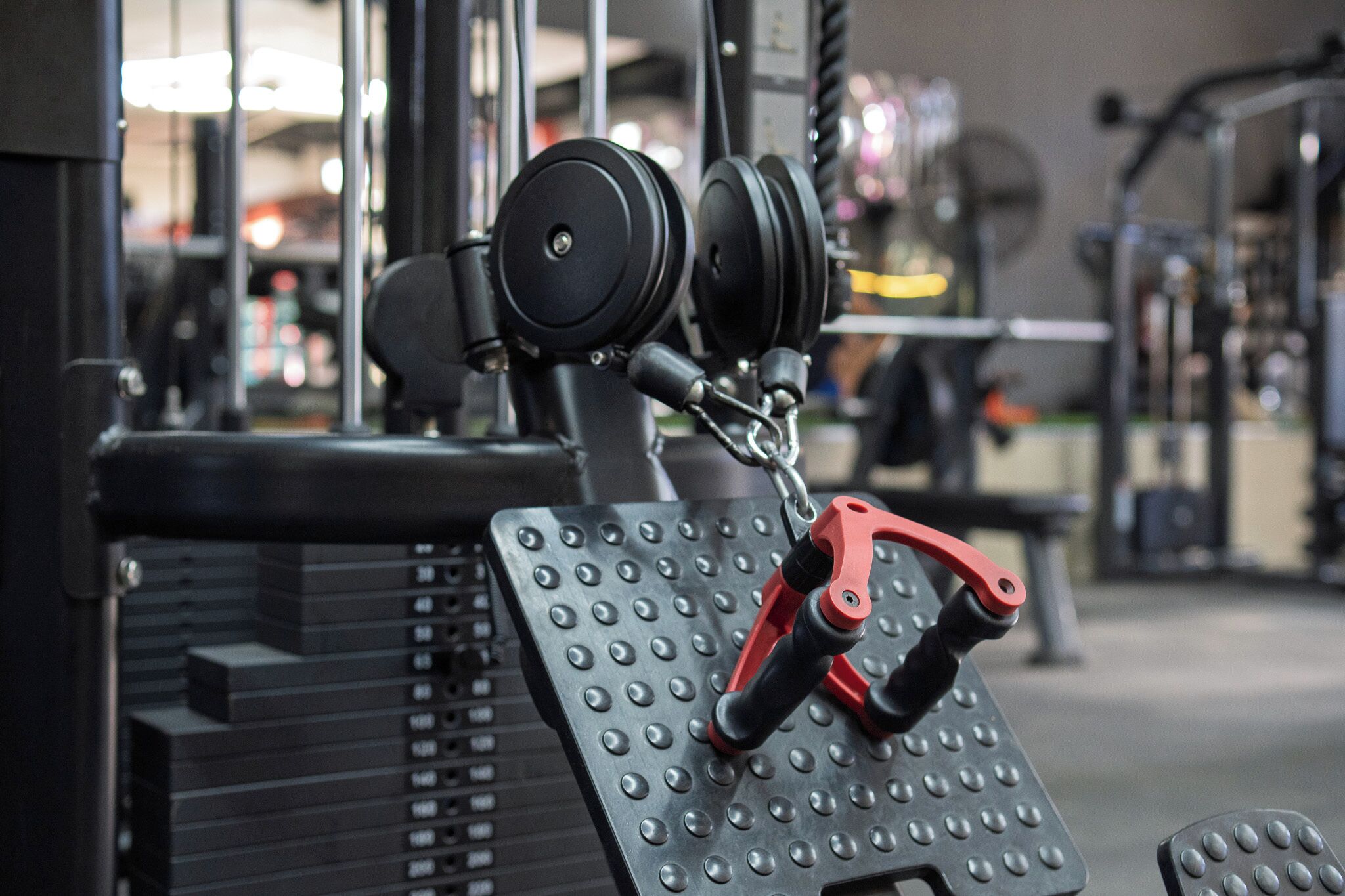 A gym equipment setup with a weight stack, pulleys, and foot pedals.