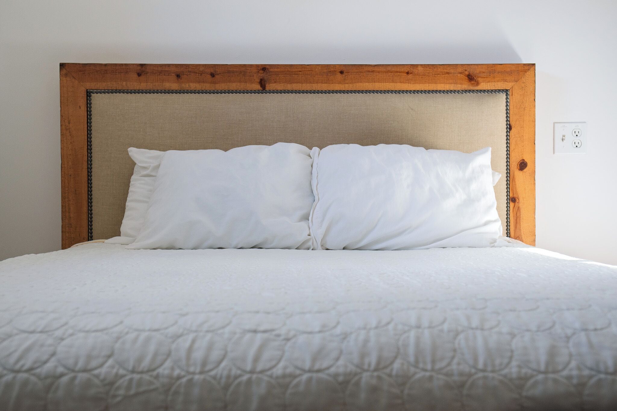 A bed with a wooden headboard and white bedding.